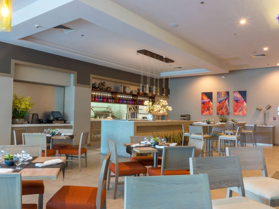 Un restaurant modern amb diverses taules i cadiretes, una zona de bar i obres d'art a les parets.