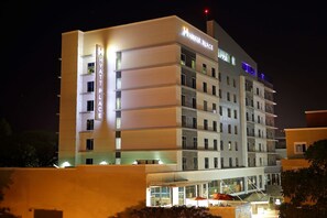 A multi-story hotel with a modern design, featuring illuminated signage and a well-lit entrance area.