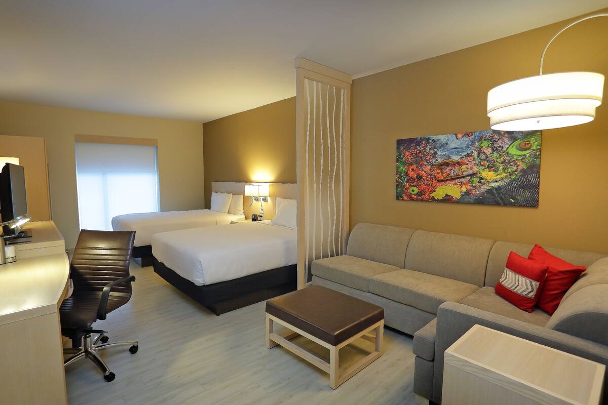 Una habitación de hotel con una cama, un sofá, un escritorio y una silla.