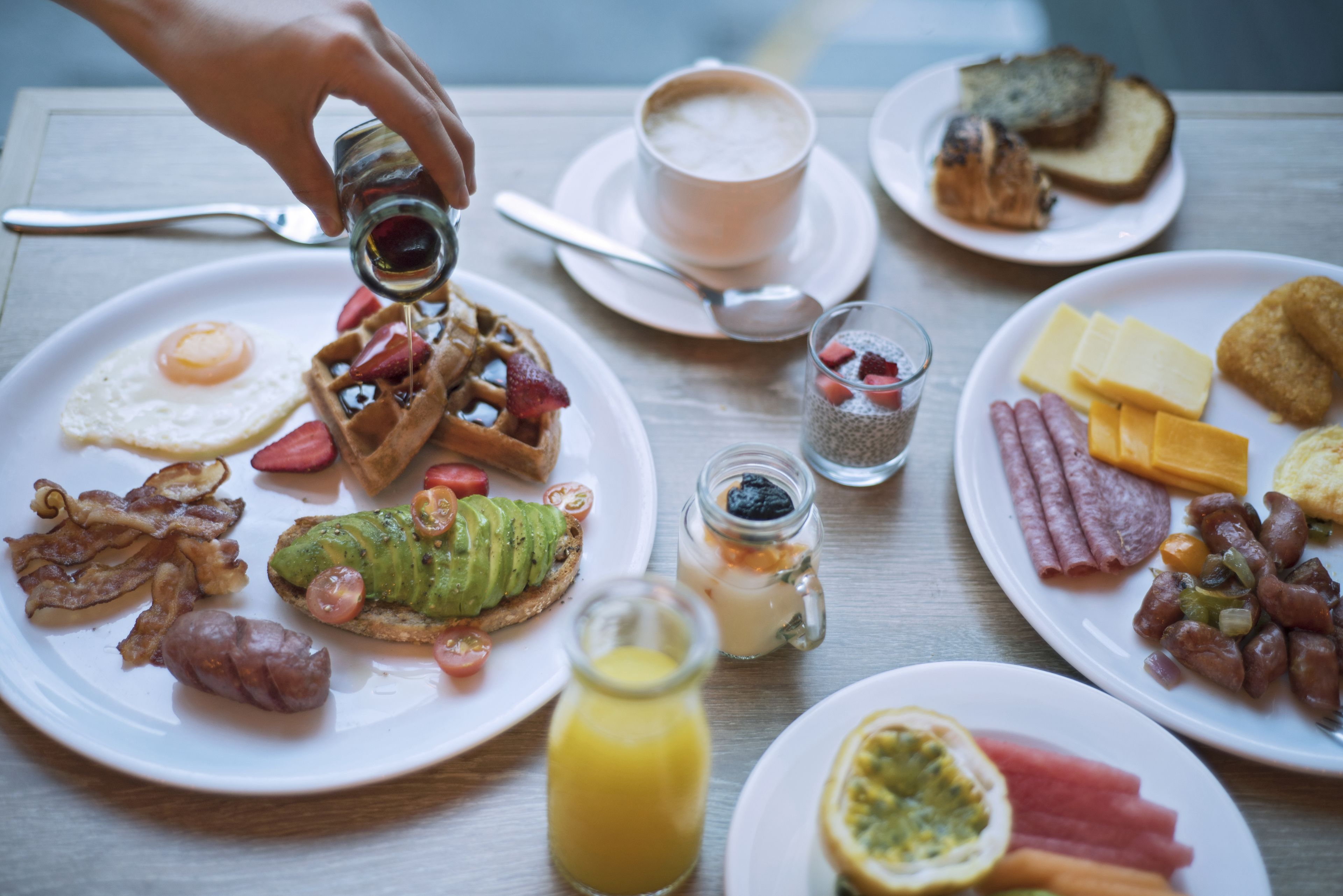 Une table de petit-déjeuner avec divers plats, notamment des gaufres, des œufs, du bacon et des toasts.
