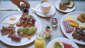 Une table de petit-déjeuner avec divers plats, notamment des gaufres, des œufs, du bacon et des toasts.