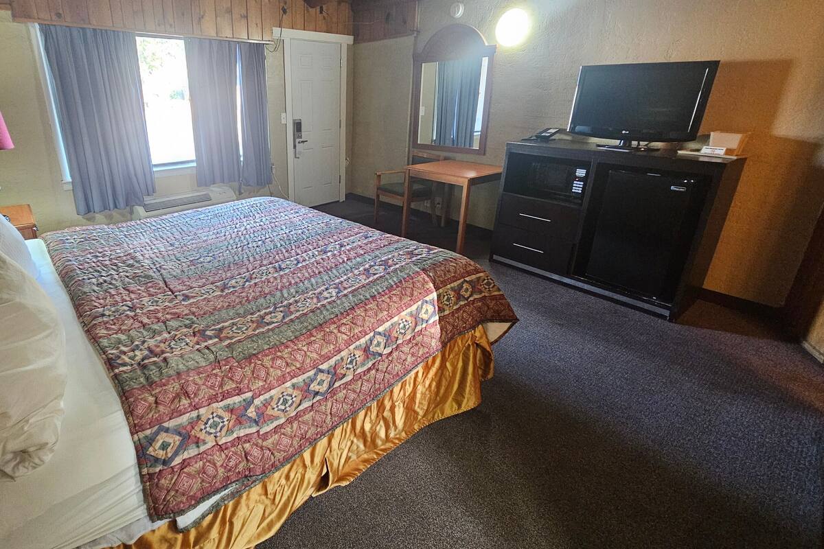 A bedroom with a bed, a desk, a television, and a wardrobe.