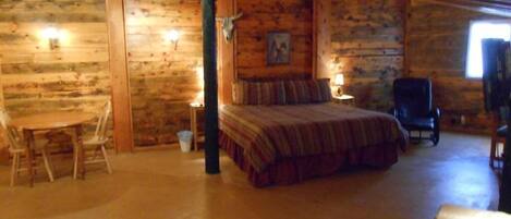 A log cabin room with a bed, a chair, a table, and a desk.