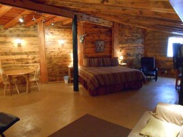 Una habitación tipo cabaña de madera con una cama, una silla, una mesa y un escritorio.