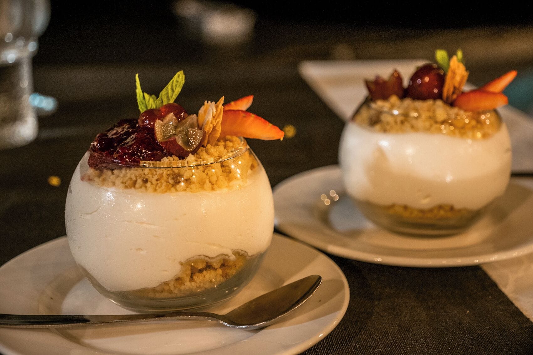 Dos tazones de postre sobre platos blancos con una cuchara.