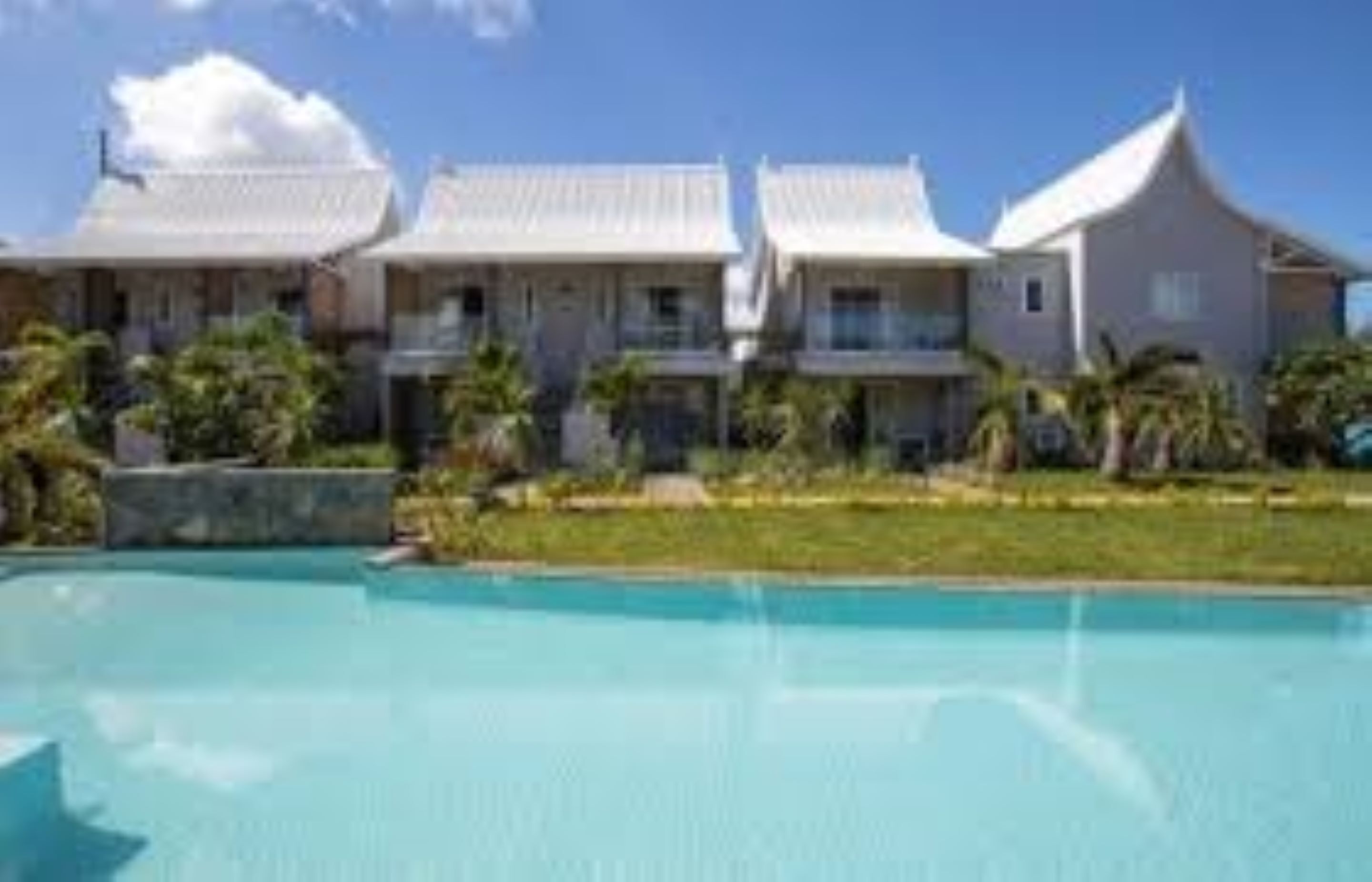 Un resort con piscina, varias villas y un césped bien cuidado.
