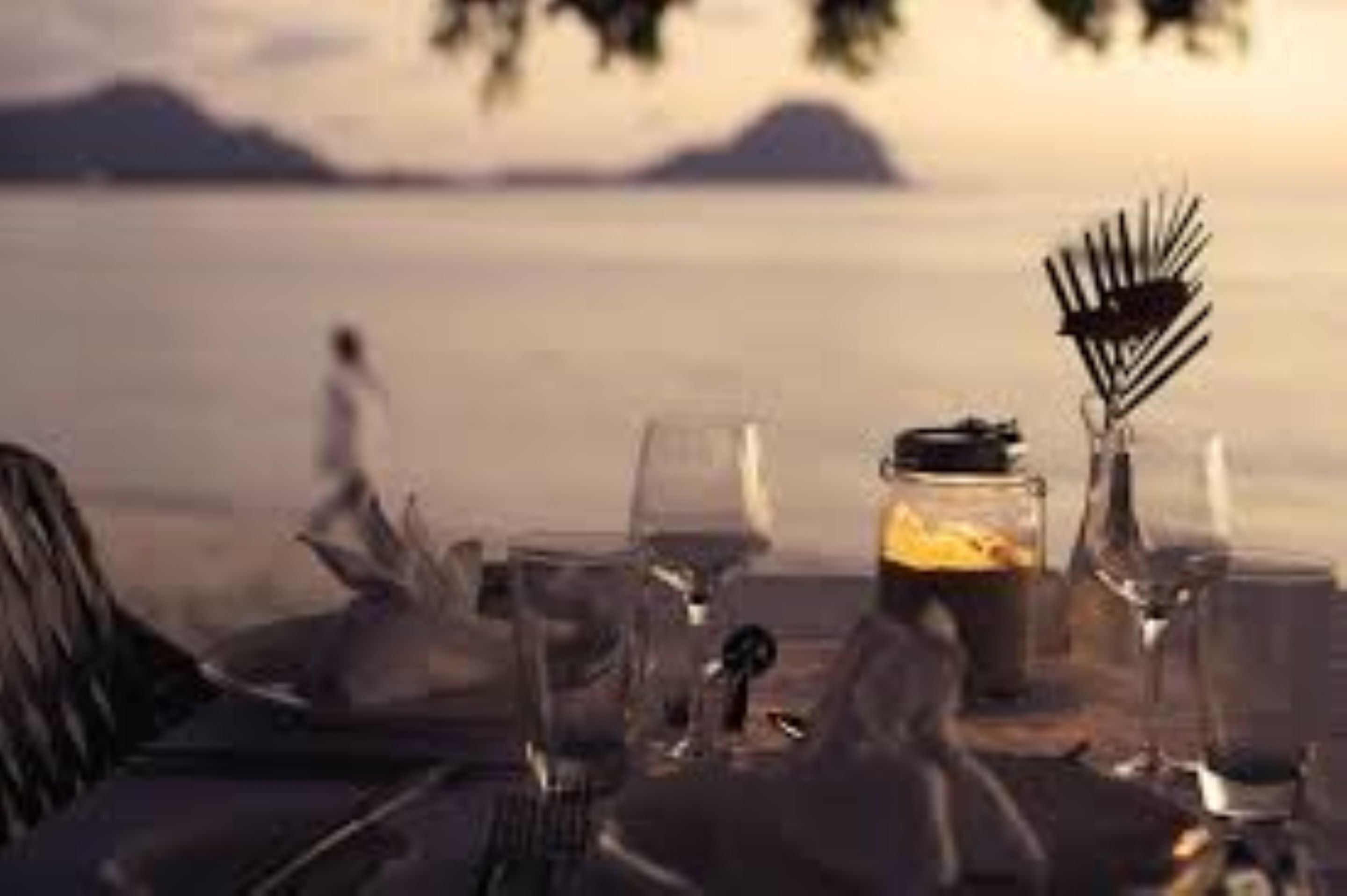 A table set for dining with a view of the sea and mountains in the background.
