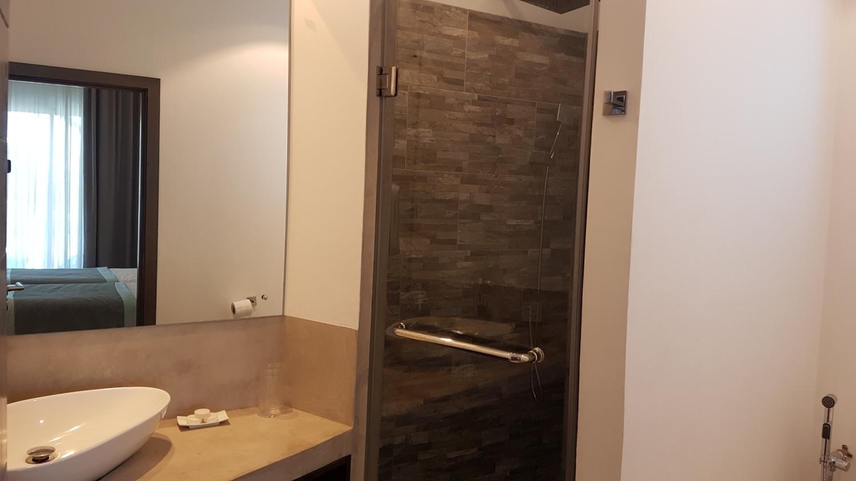 Un baño con ducha, lavamanos y espejo.