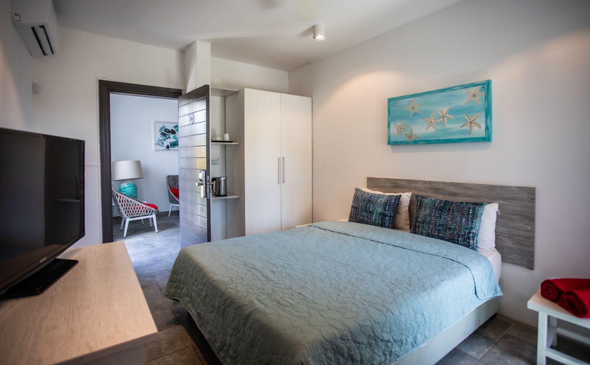 Ein modernes Hotelzimmer mit Bett, Schreibtisch, Stuhl, Kleiderschrank und einem Bild an der Wand.