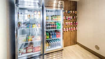 Two beverage-air coolers stocked with snacks, drinks, and condiments in a room with wooden paneling and tiled flooring.