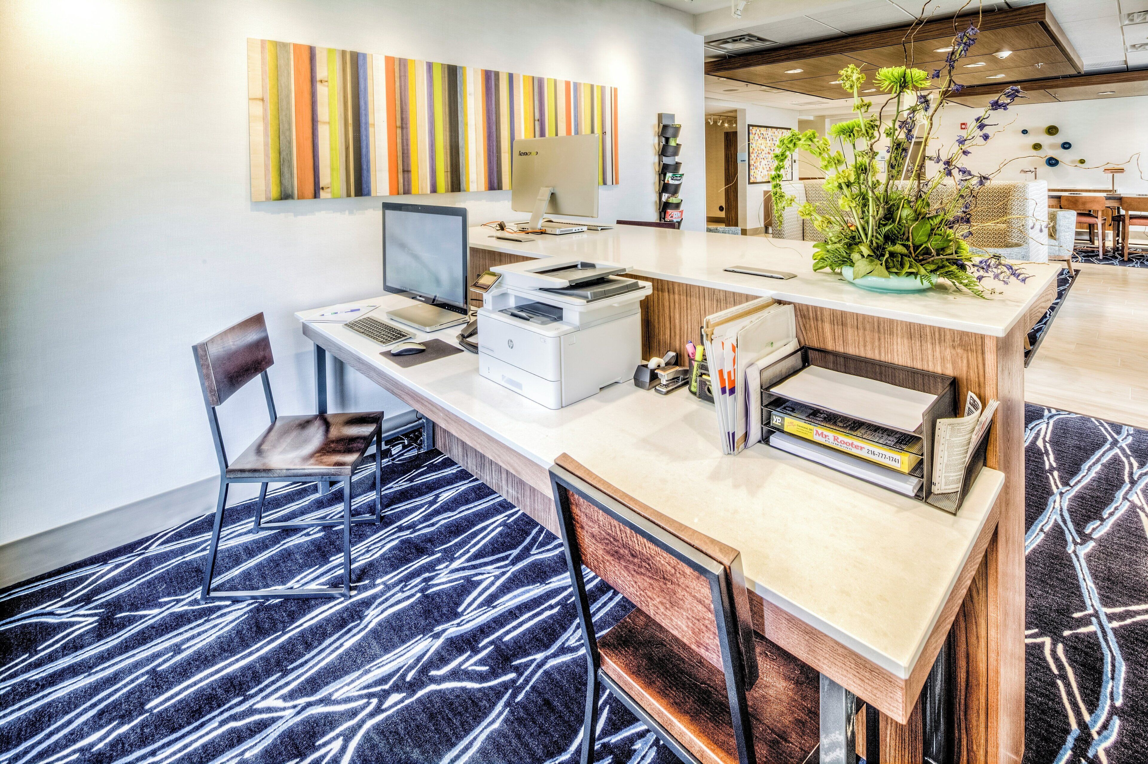 A modern office space with a desk, computer, printer, and a decorative plant.