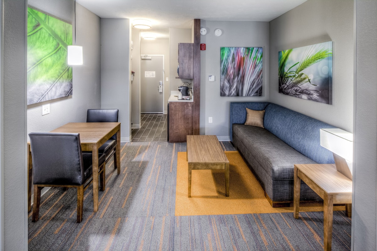 A modern hotel room with a dining area, a sofa, and a small table.