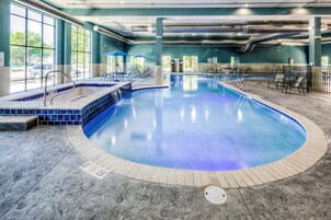 Piscina interna com borda em azulejos azuis, cadeiras de descanso e área para espreguiçadeiras.