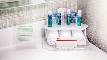 A bathroom with toiletries on a shelf, a towel, and informational signs.