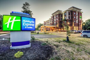 Un letrero de Holiday Inn Express & Suites con un edificio de ladrillo al fondo.