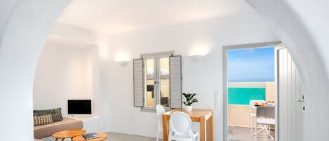 A modern, open-plan living area with a balcony, a dining table, and a sofa.
