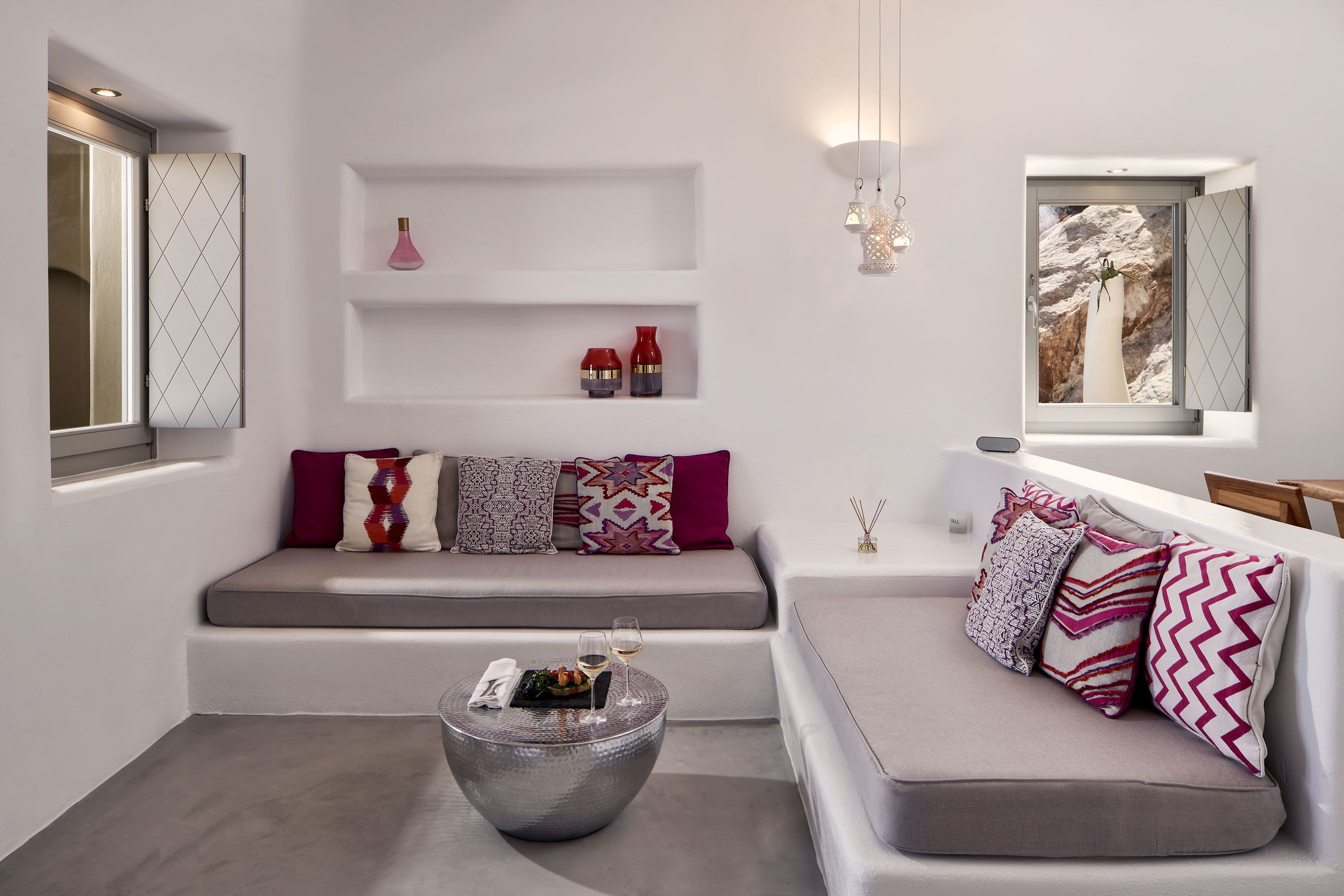 A modern living room with a grey sofa, a round coffee table, and a window with a view of a mountain.