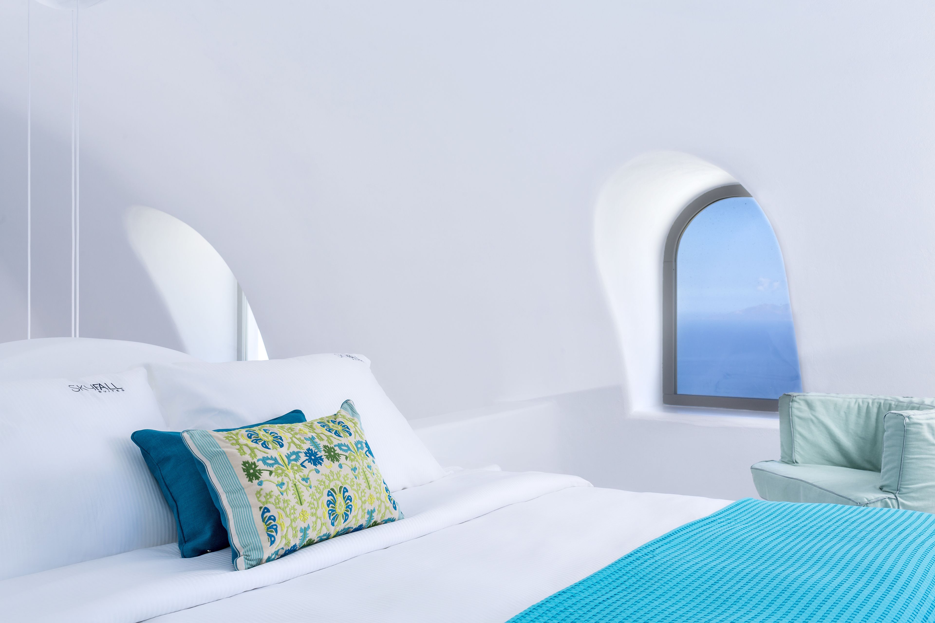 Una habitación de hotel moderna con una cama grande, un ventanal con vistas y una zona de estar pequeña.