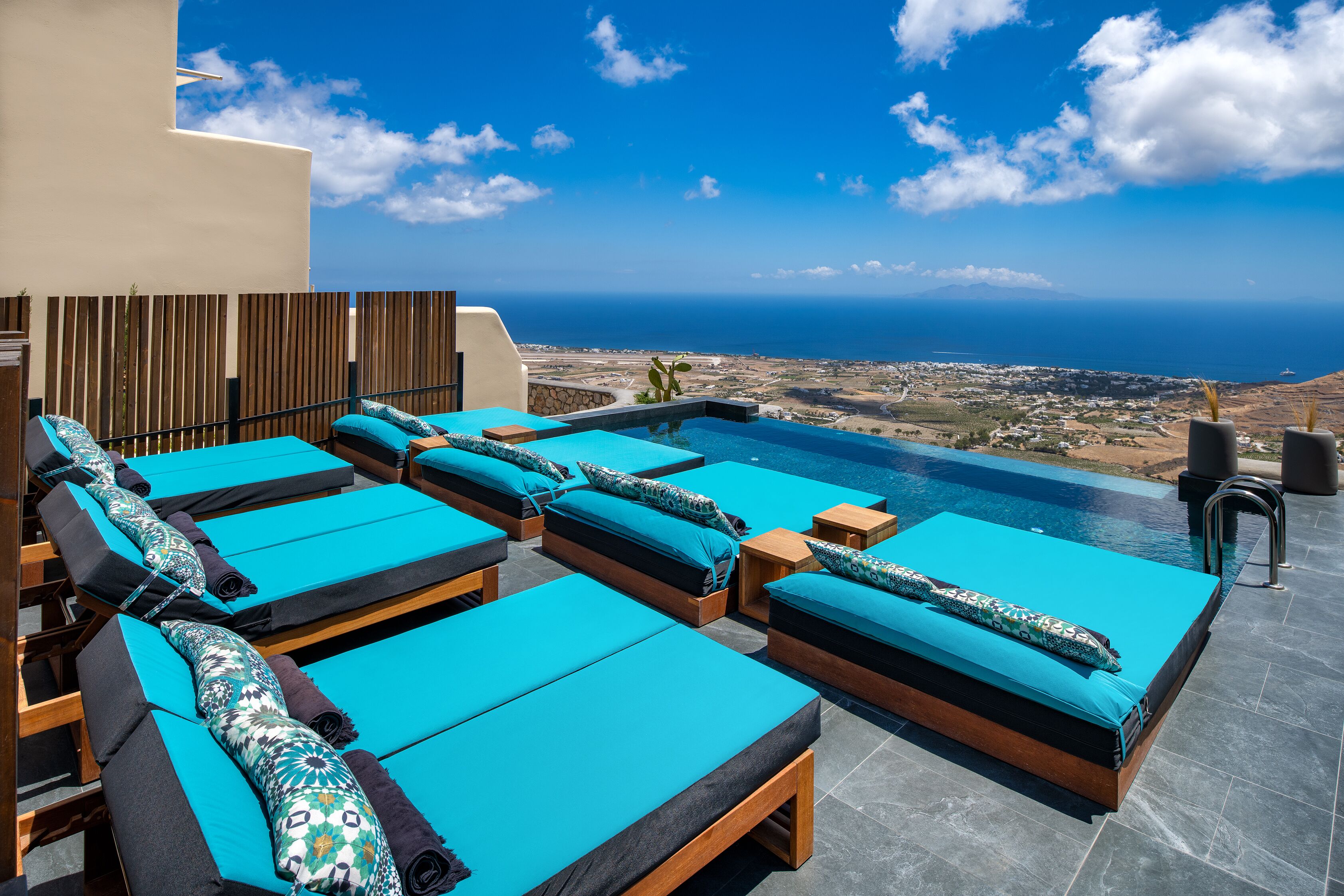 A rooftop pool area with multiple lounge chairs and a view of the ocean.
