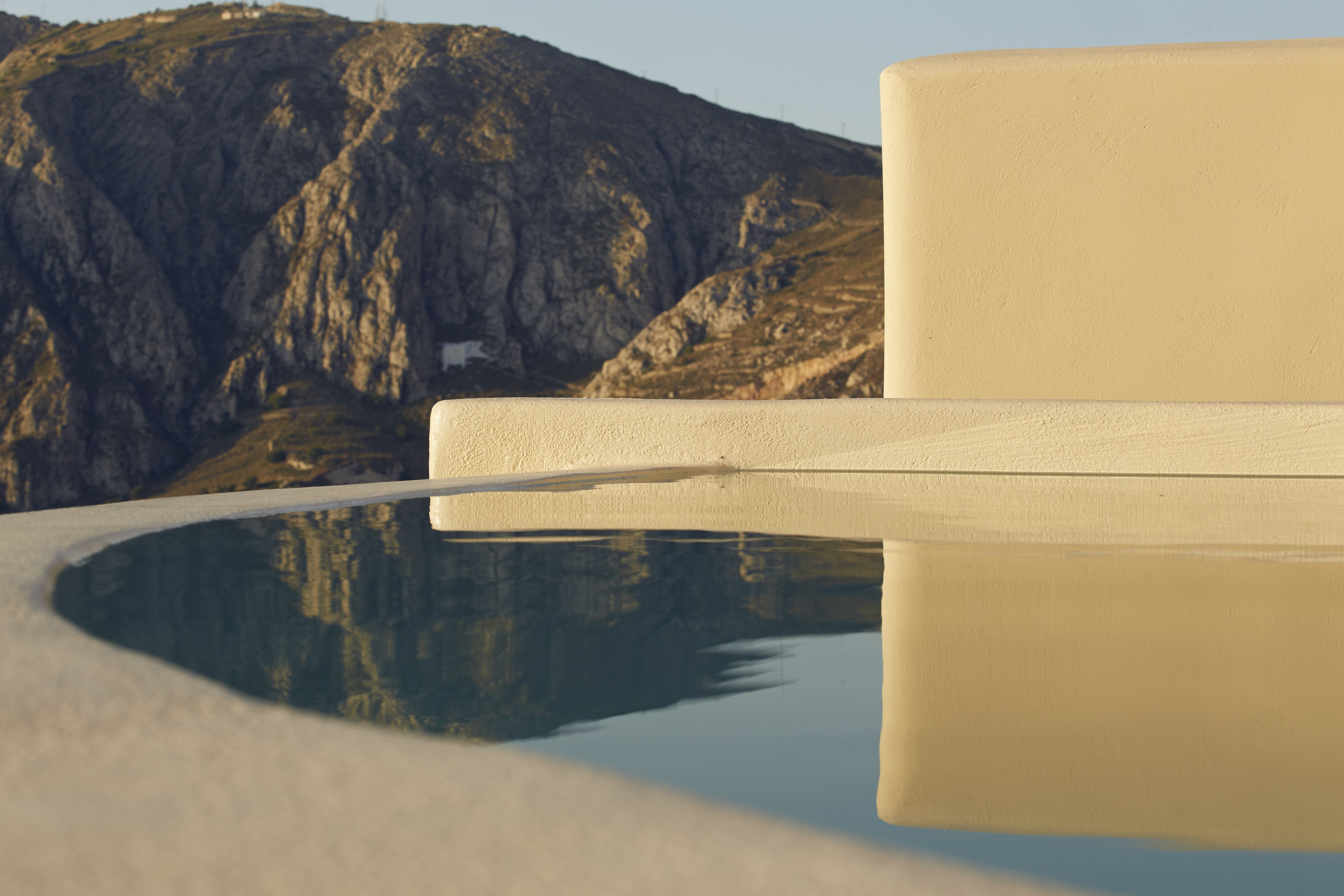A reflective pool with a mountain backdrop and a plain wall.