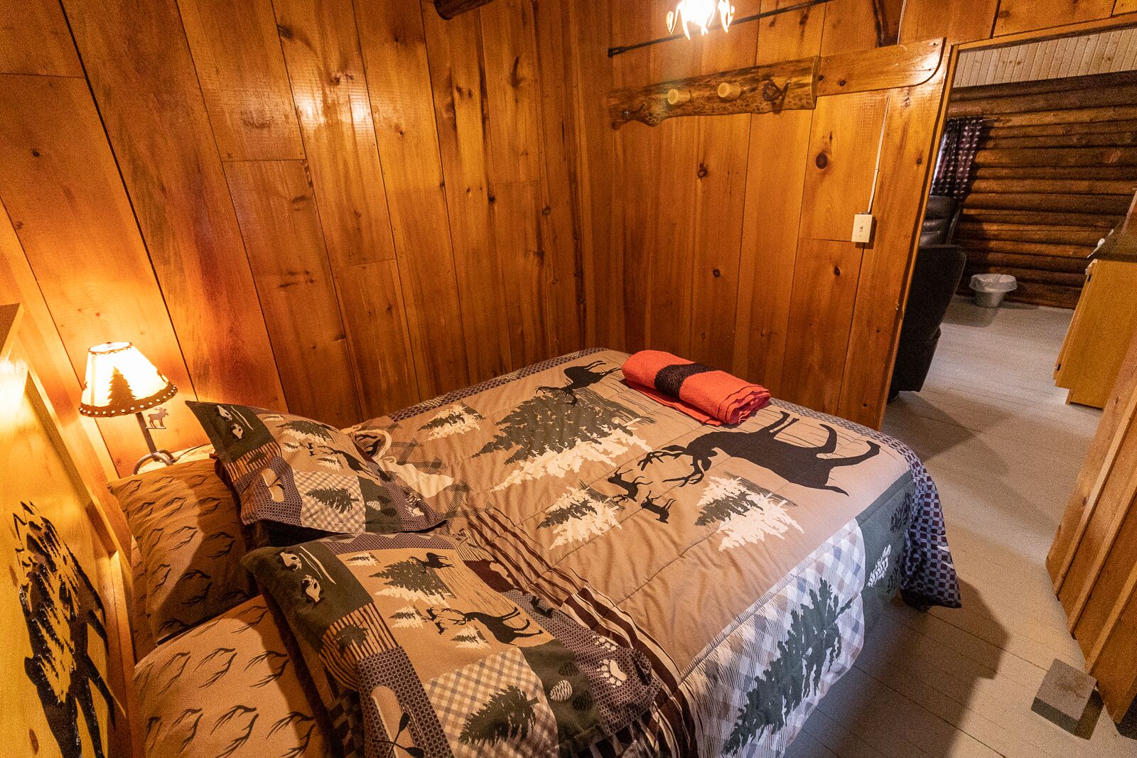 A wooden room with a bed, a lamp, and a wooden wall.
