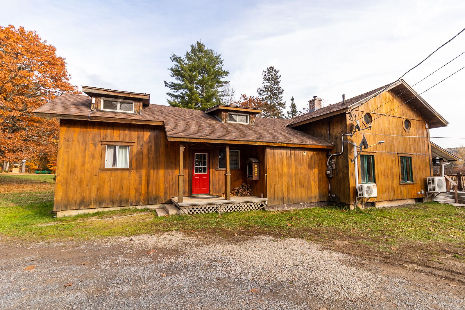 A wooden cabin with a red door, a porch, and a chimney.