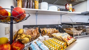 En frukostbuffé med frukt, bröd, bakverk och förpackade livsmedel.
