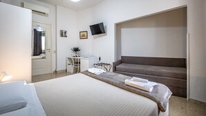 A hotel room with a bed, a desk, a chair, a TV, and a sofa. - Maison Bianca (Florence)