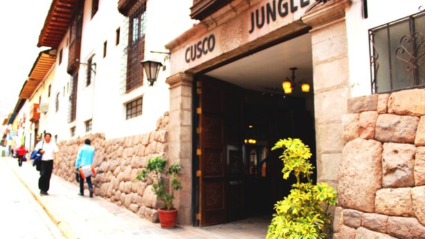 Un edificio con fachada de piedra y un cartel que dice 'CUSCO'.