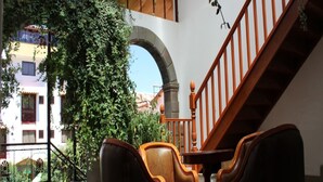 Amplio espacio interior con una escalera de madera, un gran arco y una zona de estar con sillones de cuero.