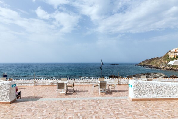 A terrace with chairs and a view of the sea.