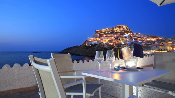Mesa para dos con vista a un pueblo costero al anochecer.