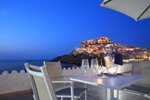 A table set for two with a view of a coastal town at dusk. - Meli Hotel (Castelsardo)