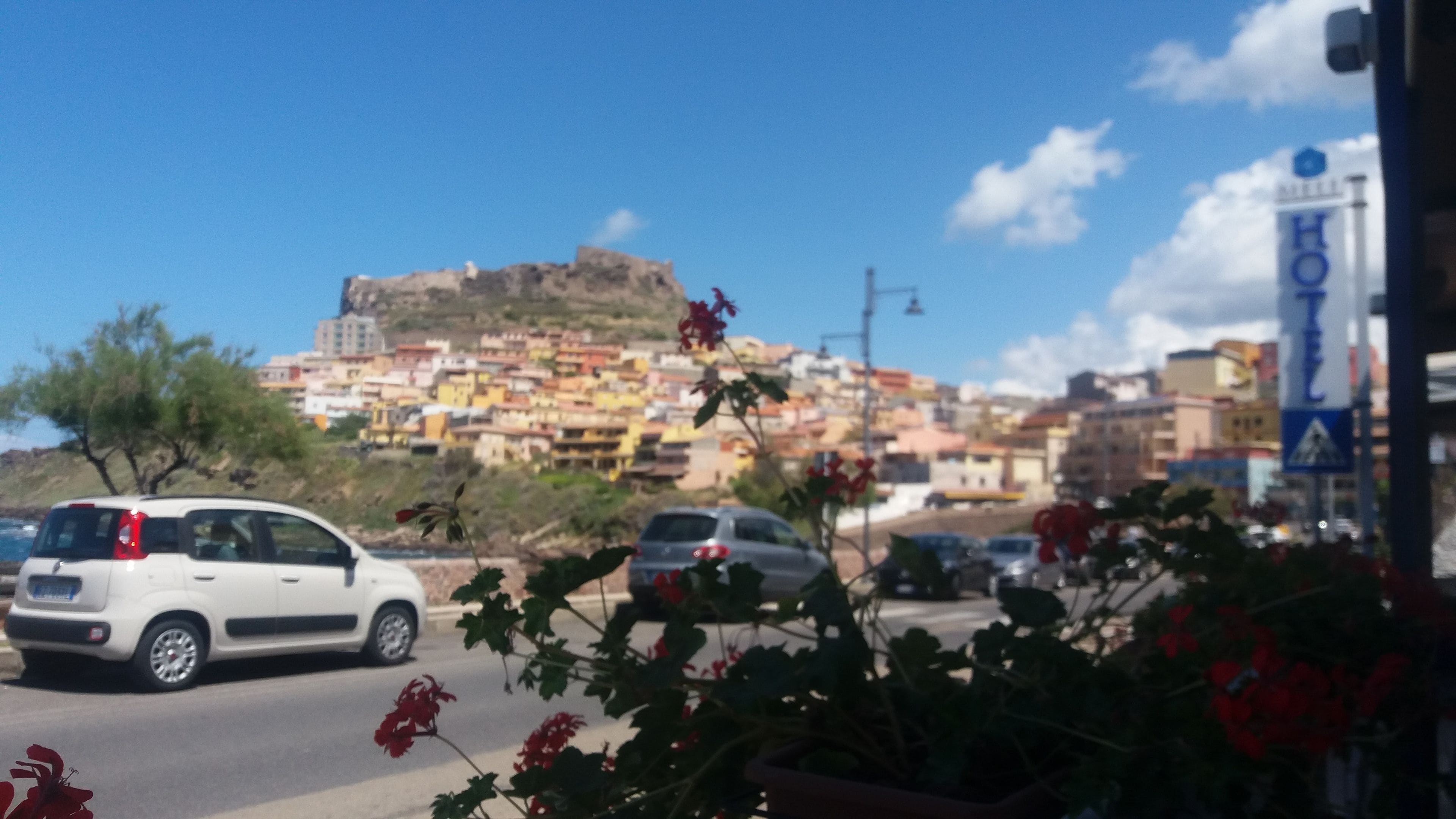 Vista de una ciudad con una colina destacada y edificios de colores al fondo.