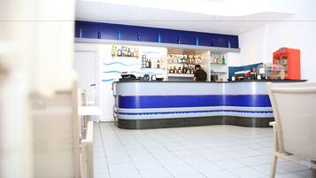A bar area with a counter, shelves of bottles, and a red machine.
