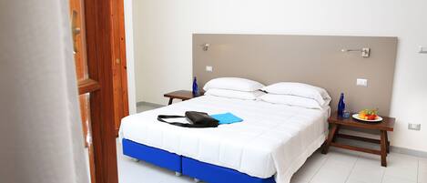 A bedroom with a bed, a bedside table, a nightstand, and a wall-mounted light.