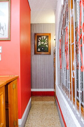 A hallway with a framed painting of white flowers and a speckled tile floor.