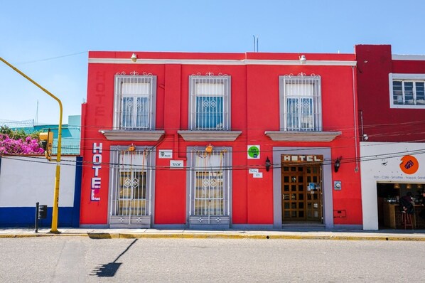 Hotel entrance with a balcony and decorative metal grilles.