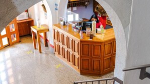 Zona de recepción con mostrador, muebles de madera y piso de baldosas.