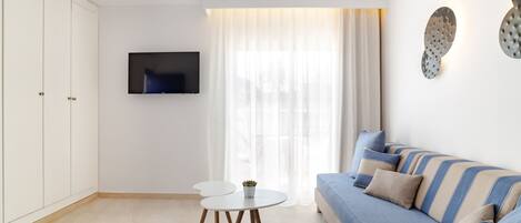 A modern living room with a sofa, a TV, a ceiling fan, and a dining table.