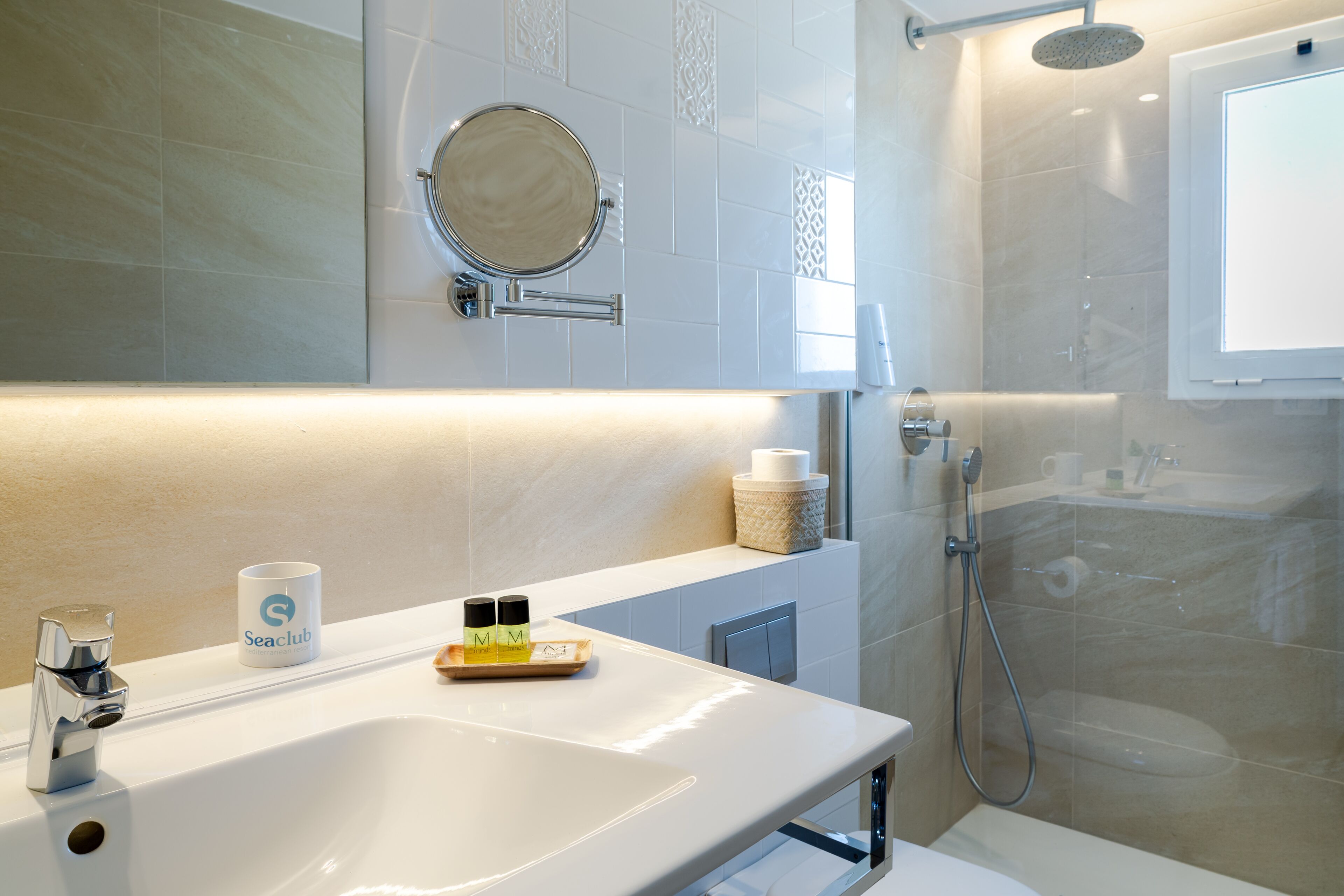 Un baño moderno con un lavamanos grande, un espejo, un cabezal de ducha de mano y un inodoro.