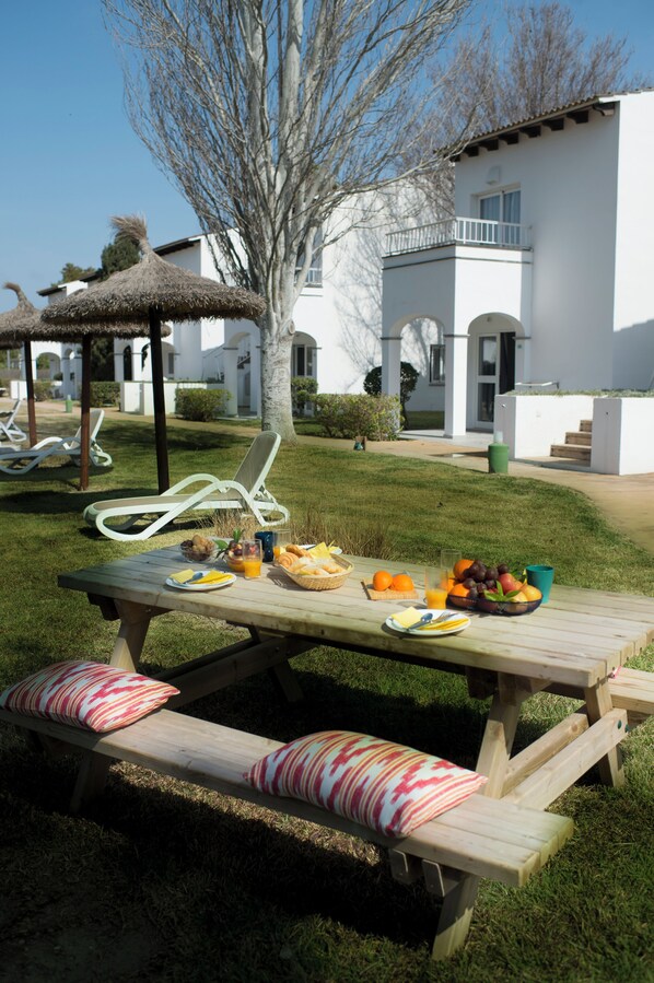 A picnic setup with a table, benches, and a basket of food. - Serenity Apartments (Alcúdia)