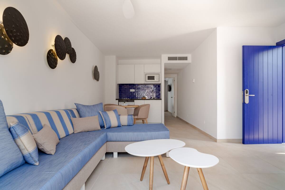 A modern living room with a sectional sofa, a dining area, and a kitchen in the background.