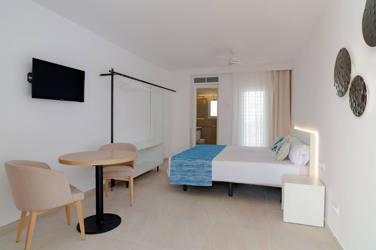A modern bedroom with a bed, bedside table, and a TV mounted on the wall.