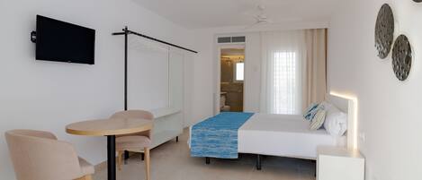 Ein modernes Schlafzimmer mit Bett, Nachttisch und einem an der Wand befestigten Fernseher.