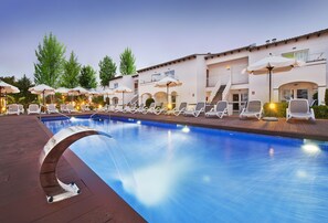 A swimming pool with lounge chairs and umbrellas, surrounded by a building with balconies and stairs. - Serenity Apartments (Alcúdia)