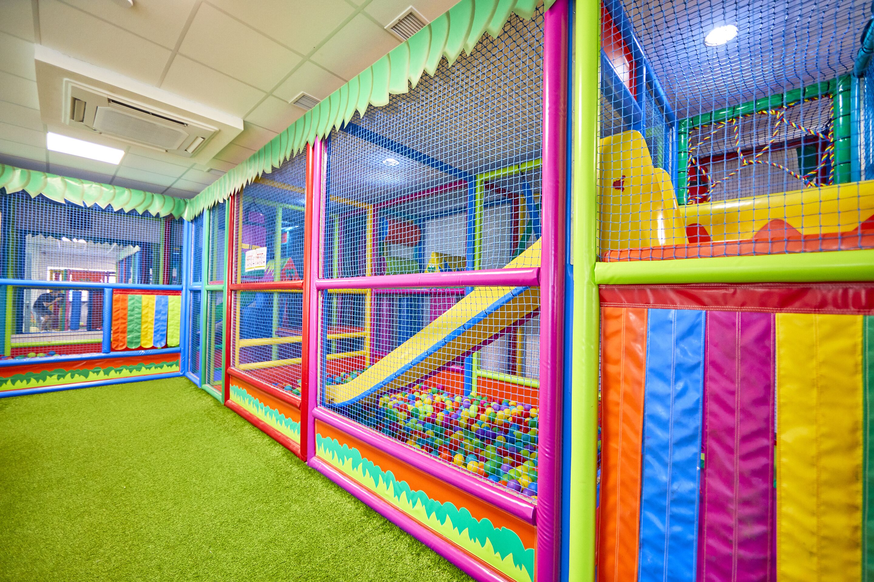 Ein Indoor-Spielbereich mit mehreren Spielgerüsten, umgeben von bunten Netzen.