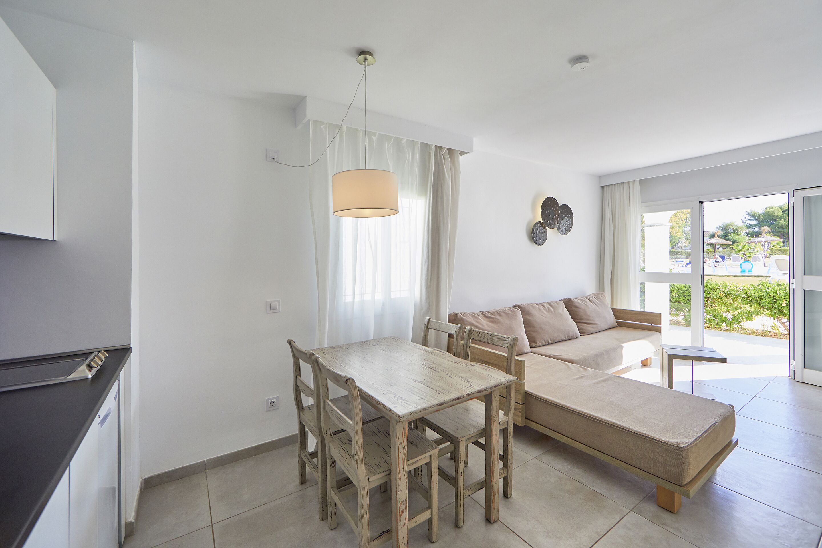 A modern living room with a dining table, sofa, and a large window offering a view of the outdoors.