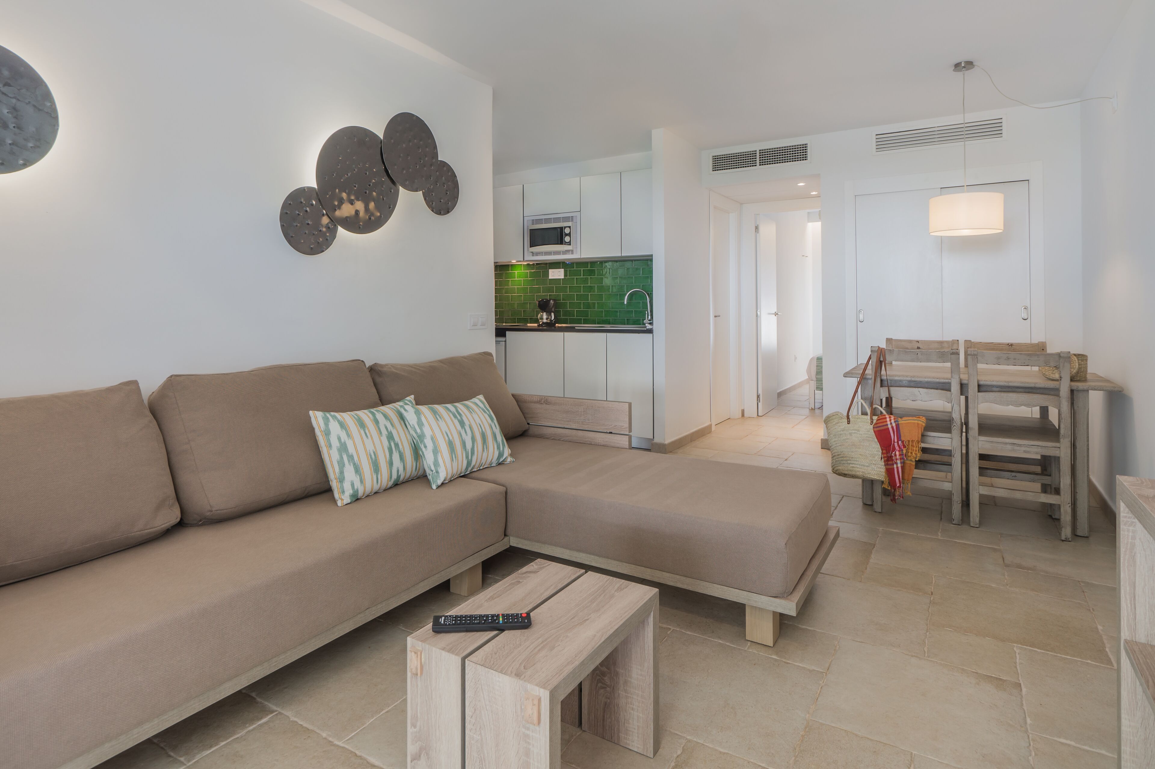 A modern living room with a sectional sofa, a small wooden coffee table, and a remote control on it.