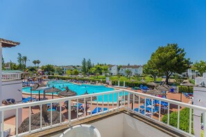 A resort pool area with multiple pools, lounge chairs, and umbrellas.